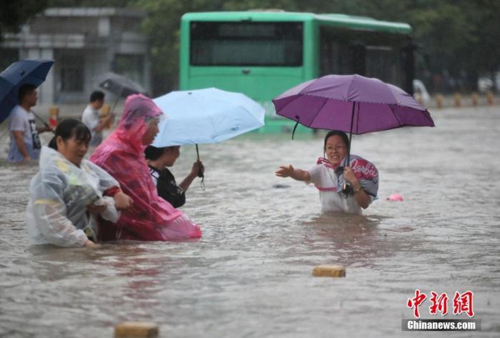 7月20日，鄭州遭遇強降雨，在經(jīng)三路、農(nóng)業(yè)路上，市民互相幫助走在齊腰深的積水里。 圖片來源：視覺中國
